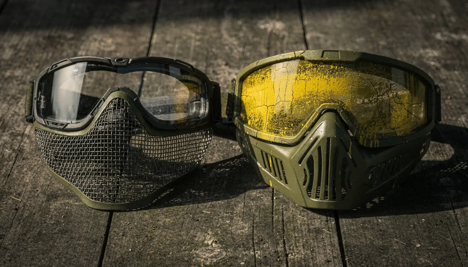 Máscara de tela usada no airsoft ao lado de uma máscara de paintball manchada de tinta amarela